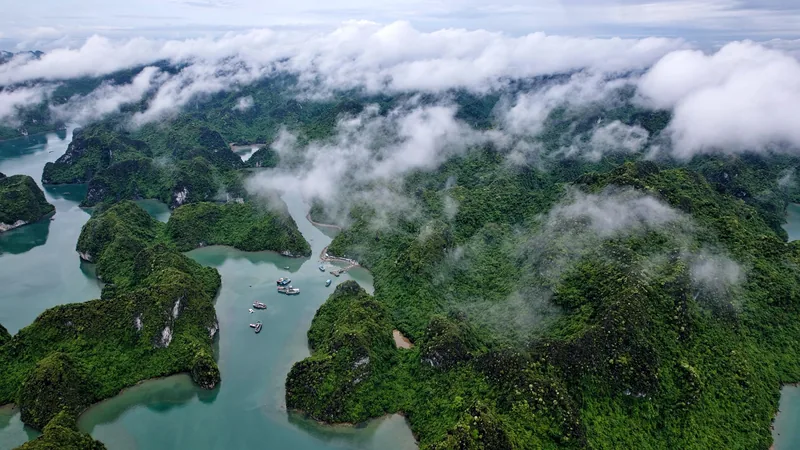 Aerial view of limestone islands and turquoise water shrouded in low clouds near Cat Ba and Lan Ha Bay