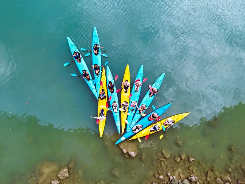 Aerial view of colorful kayaks clustered together on turquoise water near Cat Ba island.