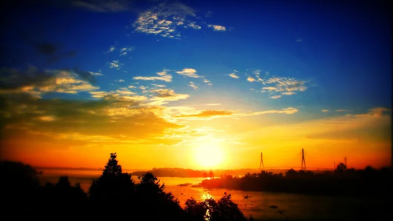 Golden sunrise over the Hau River with a cable-stayed bridge silhouetted in Can Tho, Vietnam.