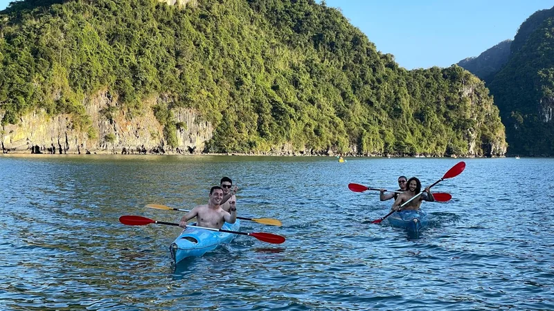 Kayakers paddle red oars beside limestone karsts in Lan Ha Bay near Cat Ba Island.