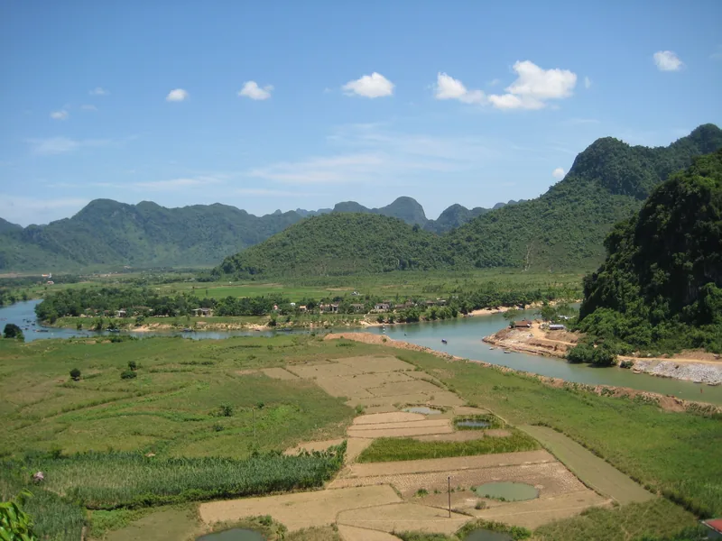 A winding river cuts through green rice fields and limestone karst mountains near Phong Nha.